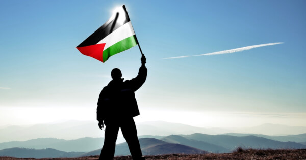 man hold a Palestinian flag face to sky